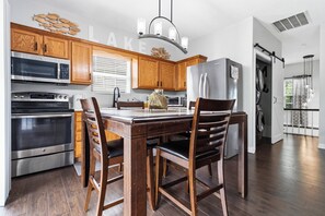Eine moderne Küche mit Holzausbau, Edelstahlgeräten und einem Essbereich mit einem Holztisch und Stühlen.