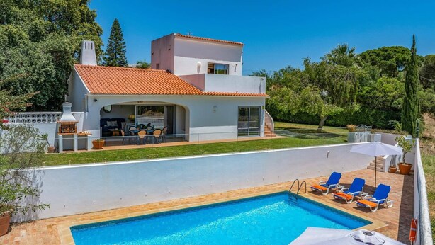 Ein modernes, zweistöckiges Haus mit Swimmingpool, Sitzgelegenheiten im Freien und Grillplatz.