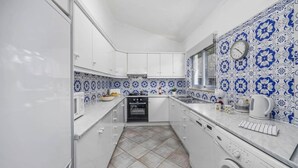 A compact kitchen with white cabinets, a built-in oven, and a washing machine.