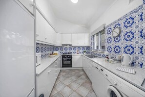 A compact kitchen with white cabinets, a built-in oven, and a washing machine.