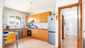 Eine Küche mit Holzausstattung, einem Edelstahlkühlschrank, einem Geschirrspüler und einem Essbereich mit Tisch und Stühlen.