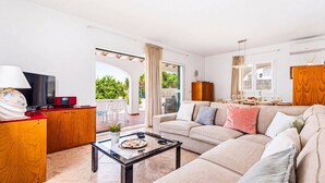 Ein modernes Wohnzimmer mit Sofa, Couchtisch, Fernseher und Blick ins Freie.