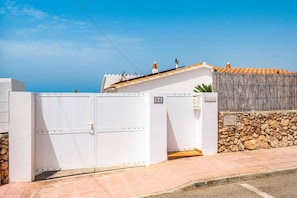 A gated property with a stone wall and a tiled roof. - Villa La Serena by Villa Plus (Cala en Porter)