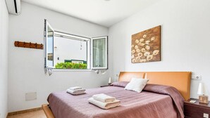 Ein Schlafzimmer mit Bett, Fenster, einem Gemälde und einem Nachttisch.
