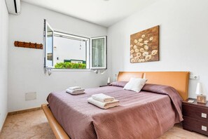 A bedroom with a bed, a window, a painting, and a nightstand. - Villa La Serena by Villa Plus (Cala en Porter)