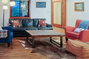 Ein Wohnzimmer mit einer Couch, einem roten Sessel, einem Holztisch und einem blauen Sessel.