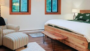 A bedroom with a bed, a chair, a bench, and two windows. - At the Mountain Mist Retreat, we believe that a true getaway starts with a restful night and a seamless morning. Our 5-bedroom, 4-bathroom layout is thoughtfully designed to provide the perfect gathering. (Wintergreen)