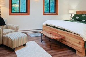 Ein Schlafzimmer mit einem Bett, einem Sessel, einer Bank und zwei Fenstern.