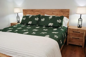 A bed with a green patterned bedspread, two bedside tables with lamps, and a wooden headboard. - At the Mountain Mist Retreat, we believe that a true getaway starts with a restful night and a seamless morning. Our 5-bedroom, 4-bathroom layout is thoughtfully designed to provide the perfect gathering. (Wintergreen)