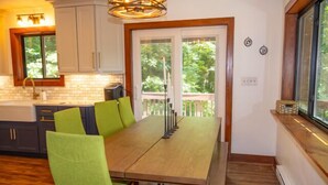 A kitchen with a dining table, chairs, and a view of the outdoors. - At the Mountain Mist Retreat, we believe that a true getaway starts with a restful night and a seamless morning. Our 5-bedroom, 4-bathroom layout is thoughtfully designed to provide the perfect gathering. (Wintergreen)