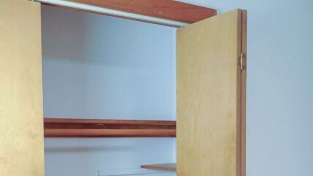 A wooden wardrobe with multiple shelves and drawers, a wooden floor, and a white wall. - At the Mountain Mist Retreat, we believe that a true getaway starts with a restful night and a seamless morning. Our 5-bedroom, 4-bathroom layout is thoughtfully designed to provide the perfect gathering. (Wintergreen)