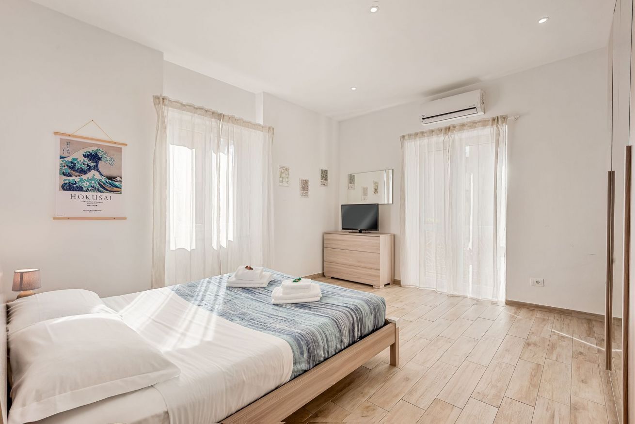 Ein Schlafzimmer mit einem Bett, einem Fernseher, einem Schminktisch und einer Wand-Klimaanlage.
