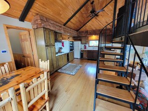 A spacious kitchen with wooden cabinets, a dining area with a table and chairs, and a staircase leading to an upper level. - Entire 2-bedroom cottage in quaint Lake Tomahawk with King Bed, AC & dock space! (Lake Tomahawk)