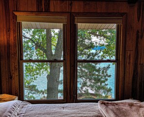 A room with a large window overlooking a tree and a body of water. - Entire 2-bedroom cottage in quaint Lake Tomahawk with King Bed, AC & dock space! (Lake Tomahawk)