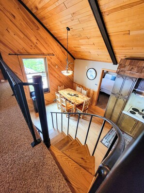 A wooden interior with a dining area, kitchen, and a staircase.