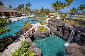 Un resort con una piscina grande, una cascada y palmeras.