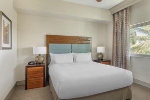 Een hotelkamer met een groot bed, twee nachtkastjes, een hoofdbord en een raam met gordijnen.