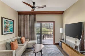 A living room with a ceiling fan, a sofa with cushions, a coffee table, a flat-screen TV, and a sliding glass door leading to an outdoor patio.