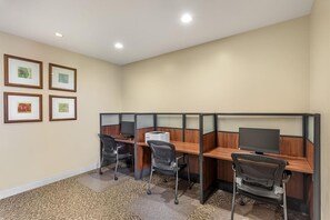 A modern office space with cubicles, desks, chairs, and framed artwork on the wall.