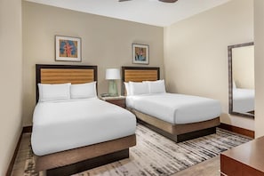 Habitación de hotel con dos camas, un espejo, obras de arte en las paredes y una alfombra estampada.