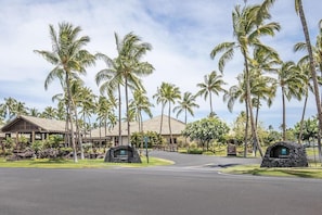 A resort with a covered walkway, palm trees, and a Clubhouse sign.