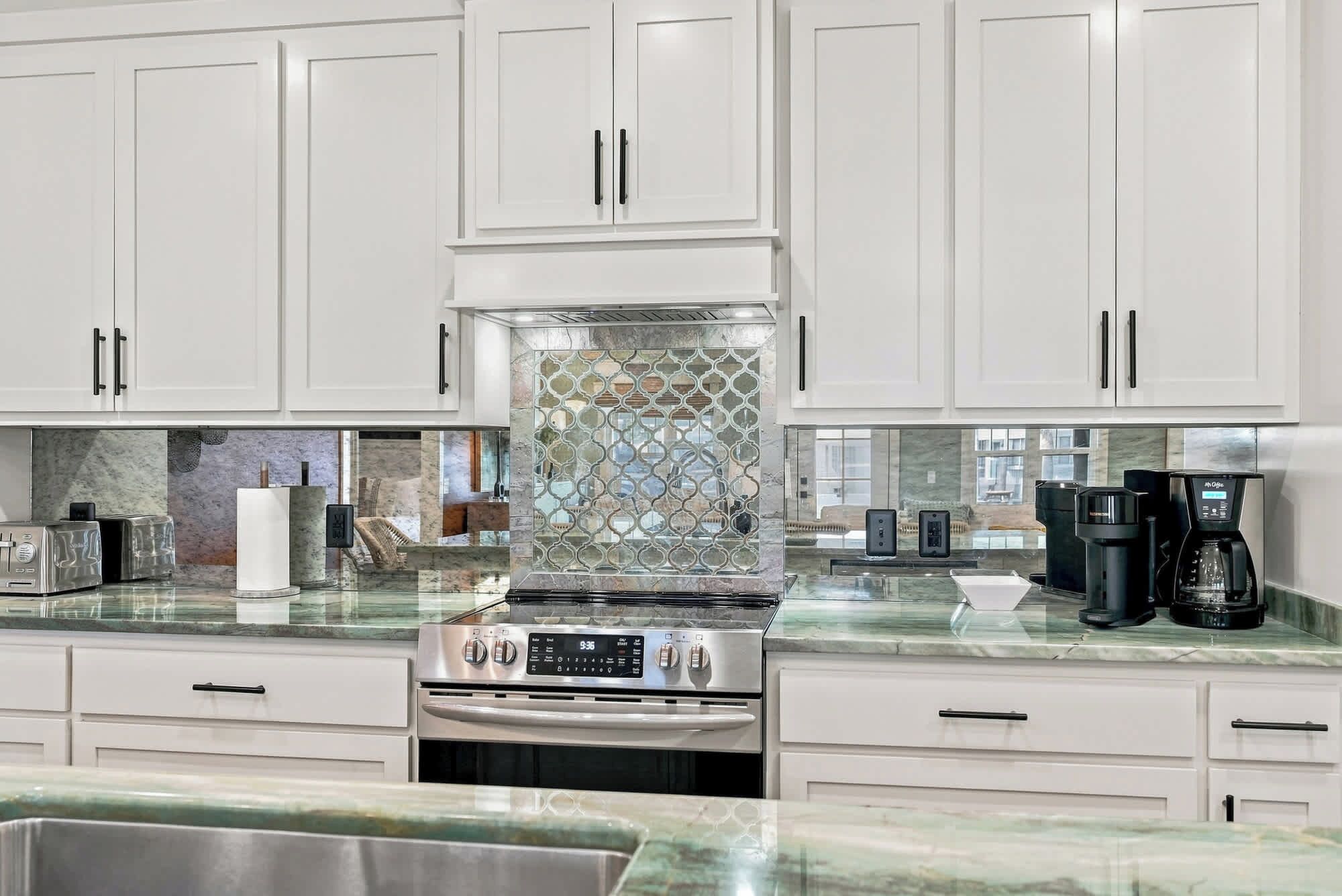 A kitchen with white cabinets, a stainless steel range, and a glass backsplash.