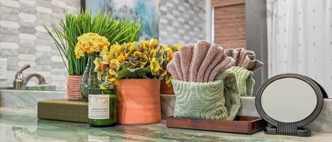 Un tocador de baño con espejo, una botella de Chardonnay y plantas decorativas.