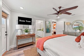 A bedroom with a bed, a desk with lamps, a ceiling fan, and a 'Home Team' sign. - PCB Getaway • Resort Amenities • Golf Cart • Pools (Panama City Beach)