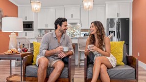 Una sala de estar moderna con un sofá, una mesa de centro y un comedor con una cocina al fondo.