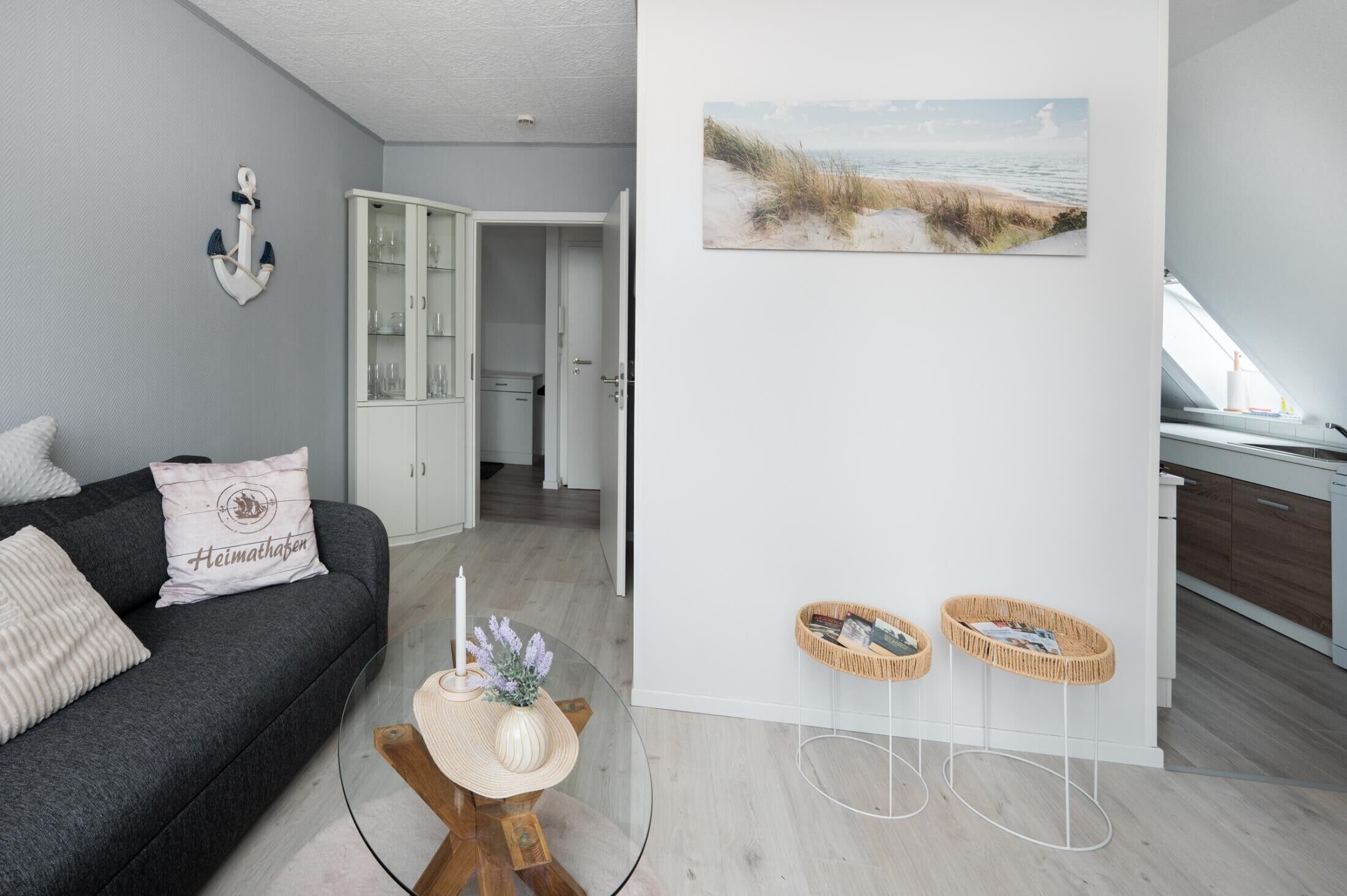 A modern living room with a grey sofa, a glass coffee table, and a wall-mounted picture.