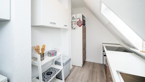 Eine kleine Küche mit weißen Schränken, einem eingebauten Backofen und einer Arbeitsplatte.