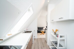 A modern kitchen with a skylight, a dining area with a glass table, and a living room with a sofa and a coffee table. - Apartment 'Katja' with Private Terrace and Wi-Fi (Büsum)