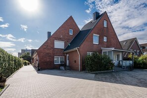 Ein Wohngebäude mit Backsteinfassade, geneigtem Dach und gepflasterter Auffahrt.