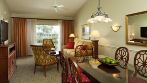 A hotel room with a dining area, a television, a ceiling fan, and a large window with curtains. - Port St. Lucie | Golf Retreat | Pool + Spa | 2BR (Port St. Lucie)
