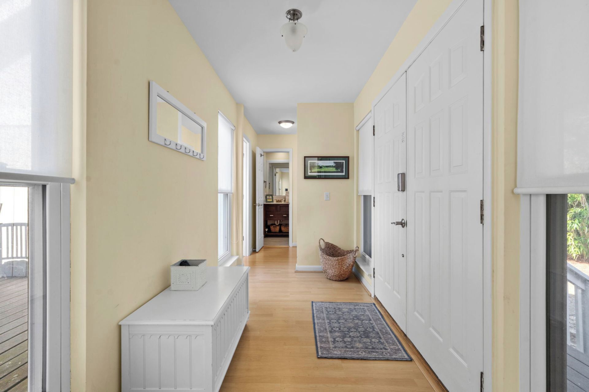 A hallway with a white bench, a rug, and a basket.