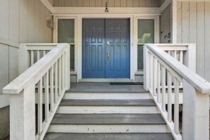 Holzstufen führen zu einer blauen Tür, an jeder Seite eine weiße Handläufe.