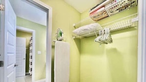 En smal gang med en dør der fører til et værelse, en radiator og en hylde med sammenfoldede ting.