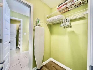 A narrow hallway with a door leading to a room, a radiator, and a shelf with folded items. - Beachside Condo in Miramar Beach (Destin)
