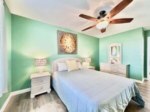 A bedroom with a bed, nightstands, a ceiling fan, and a wall-mounted mirror. - Beachside Condo in Miramar Beach (Destin)