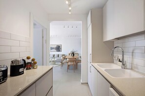 A modern kitchen with white cabinetry, a double sink, and a coffee machine. - 3-bedroom duplex apartment in gorgeous Jerusalem with mamad (Jerusalem)