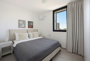 A hotel room with a bed, a nightstand, a window with curtains, and two wall-mounted artworks. - 3-bedroom duplex apartment in gorgeous Jerusalem with mamad (Jerusalem)