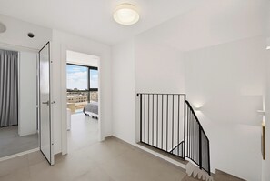 Un appartement moderne doté d’un balcon, d’un escalier et offrant une vue sur le paysage urbain.