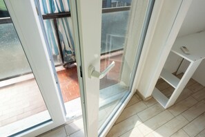 A room with a sliding glass door leading to an outdoor area with a metal gate and a tiled floor. - Niguarda Suite (Milano)