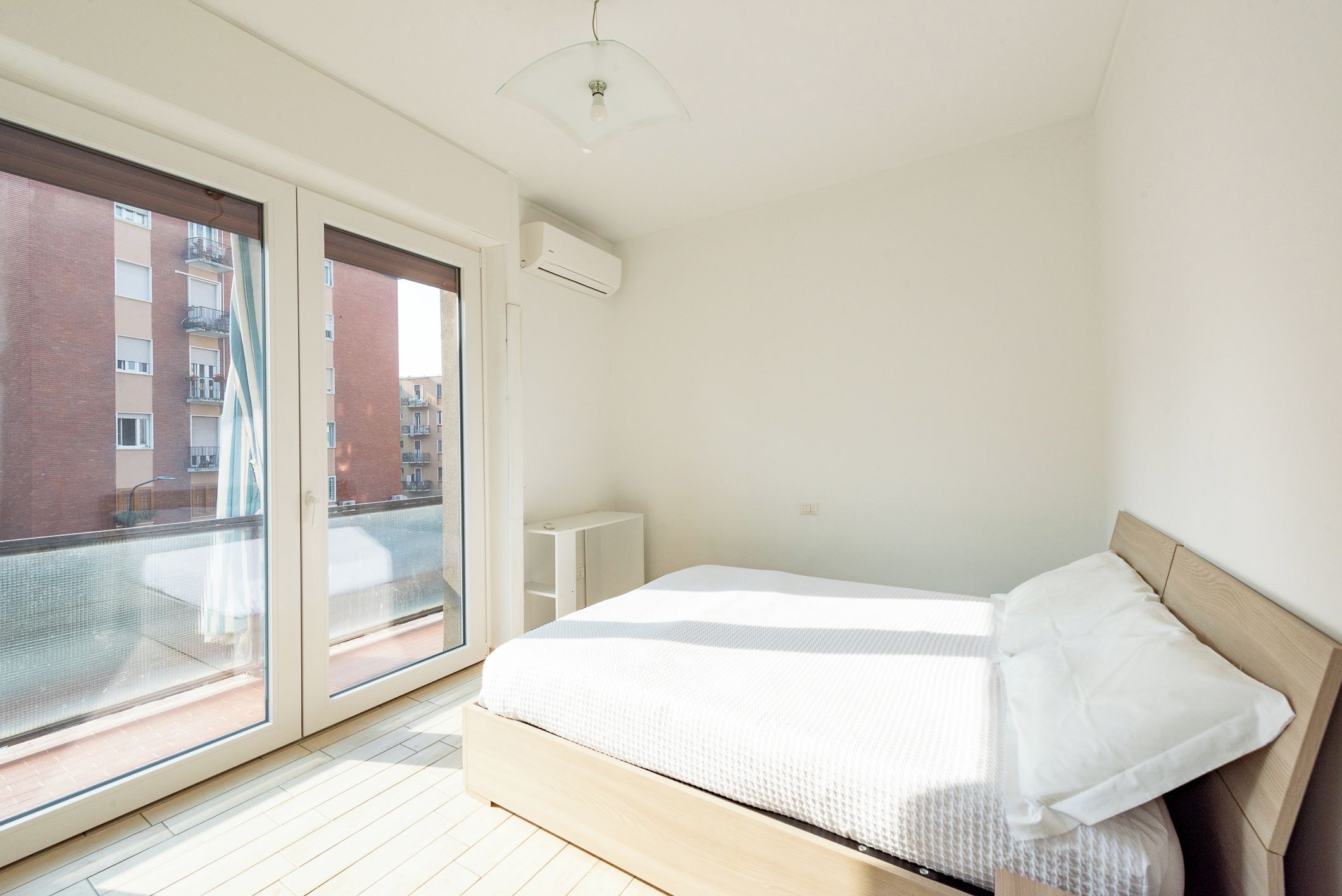 Une chambre à coucher avec un lit, une fenêtre et une vue sur des immeubles.