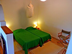 Ein Zimmer mit zwei Betten, einem Nachttisch mit Lampe, einem Sessel und einer Pendelleuchte.