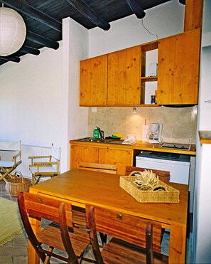 A compact kitchen with wooden cabinets, a dining table with chairs, and a coffee maker. - Quinta Sonhos, for romantic nature lovers, Lagos (Lagos)