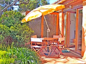An outdoor patio with a wooden table and chairs, a yellow umbrella, and a view of the surrounding greenery. - Quinta Sonhos, for romantic nature lovers, Lagos (Lagos)
