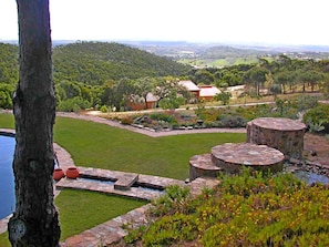Ein angelegter Garten mit Pool, Steinarchitektur und Blick auf die umliegenden Hügel.
