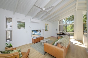 A spacious living room with a large window, a ceiling fan, and a view of the outdoors.