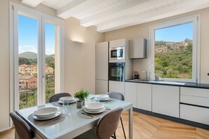 A modern kitchen with a dining area, large windows, and a view of the city. - [Residenza la Guercia]Seaview-5 terre-A/C (La Spezia)